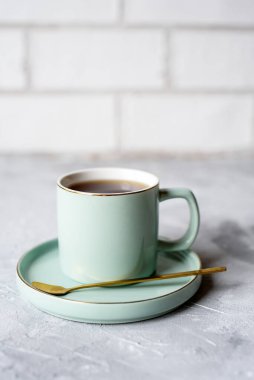 Güzel bir fincan çay tabağı ve beton bir arka planda kaşık. Çay fincanı ile aydınlık arka plan. Kokulu sabah çayı..