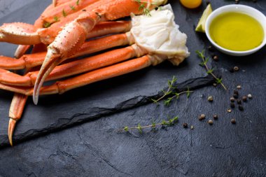 Taze yengeç pençeleri, kireç, baharatlar, baharatlar, buz, karides, arka planda sebzeler. Lezzetli deniz ürünleri sağlıklı yiyecekler