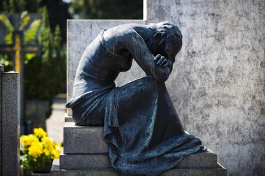 Statues of mourning at the graves of the monumental cemetery in Milan. clipart
