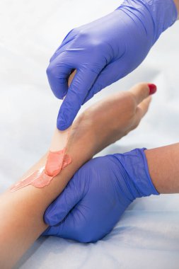 Güzellik salonunda kadın bacakları ve elleri inceleniyor. 