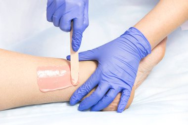 Güzellik salonunda kadın bacakları ve elleri inceleniyor. 