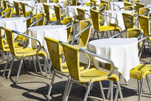 Rows of tables and chairs on the street in a restaurant