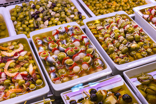 Canapes on wooden sticks of ecological products without GMO seafood and vegetables on the market in Spain, Barcelona.