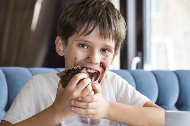 Oğlan elinde büyük bir dilim pasta yiyor 