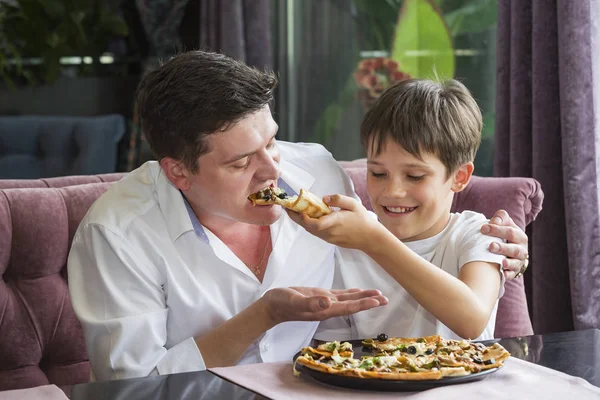 Father son eating an Italian pizza at a pizzeria