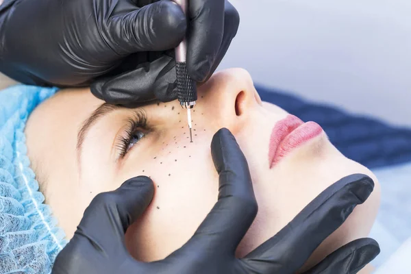 permanent microblading tattooing freckles to a woman in a beauty salon