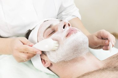 Genç bir adam bir güzellik salonu spa bir maske tedavisi geçiyor.