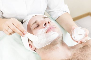 Genç bir adam bir güzellik salonu spa bir maske tedavisi geçiyor.