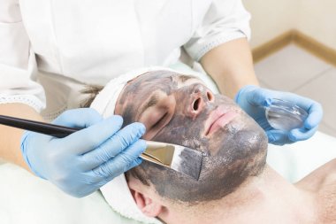 Genç bir adam bir güzellik salonu spa bir maske tedavisi geçiyor.