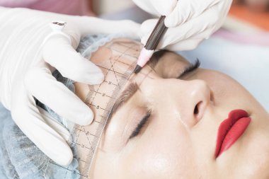 Güzellik salonunda genç bir kadının kaşlarının düzeltilmesi.