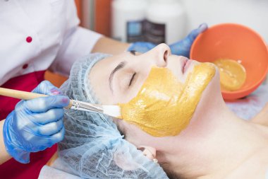 Güzellik salonunda demir ve demir dışı metallerin bileşenlerinin bir maske ile bir kadının yüzüne kişisel bir maske uygulayarak prosedür.