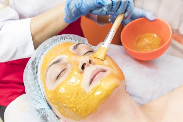 Güzellik salonunda demir ve demir dışı metallerin bileşenlerinin bir maske ile bir kadının yüzüne kişisel bir maske uygulayarak prosedür.