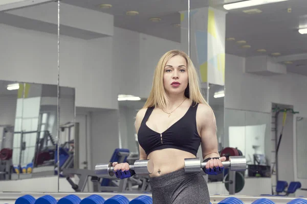 A girl in a gym with a shaker with a sports nutrition