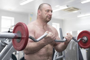 Orta yaşlı adam spor salonunda vücut geliştirme için gidiyor.