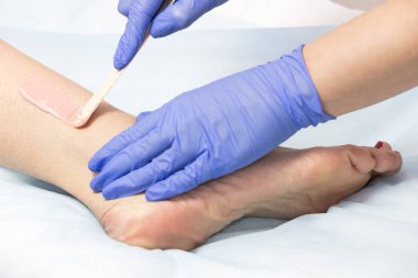 Bir güzellik salonunda kadın vücut parçalarının yakın çekim depilasyon süreci.