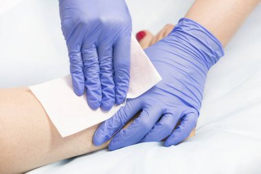 Bir güzellik salonunda kadın vücut parçalarının yakın çekim depilasyon süreci.