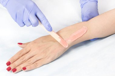 Bir güzellik salonunda kadın vücut parçalarının yakın çekim depilasyon süreci.