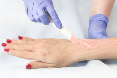 Bir güzellik salonunda kadın vücut parçalarının yakın çekim depilasyon süreci.