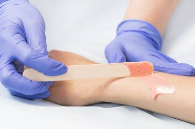 Bir güzellik salonunda kadın vücut parçalarının yakın çekim depilasyon süreci.