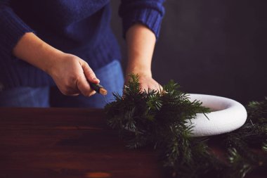 Kadın çiçekçi dalları üzerinde Noel çelenk sabitleme