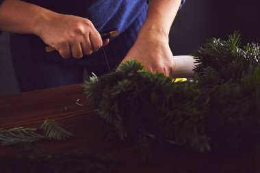 Kadın çiçekçi dalları üzerinde Noel çelenk sabitleme