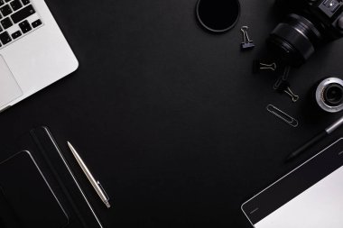 Latptop, kamera, lensler ve fotokopi alanı ile günlük ile fotoğrafçı tabloüst görünümü. Siyah arka plan üzerinde düz yatıyordu.