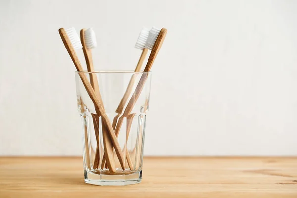 Empat sikat gigi bambu dalam gelas di atas meja kayu — Stok Foto