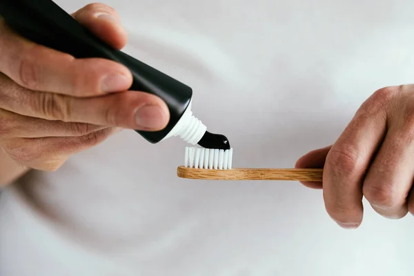 Siyah diş macunu ve bambu diş fırçası ile erkek elleri