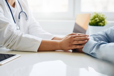 Kadın doktor hastaya güven veriyor ve ellerini tutuyor