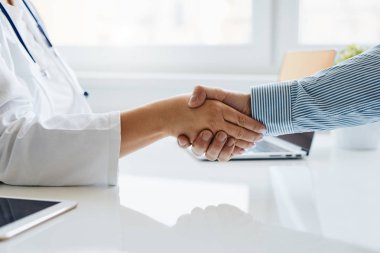 Kadın doktor hastasıyla el sıkışıyor