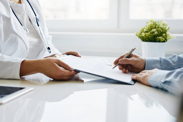 Patient signs a medical report with his doctor