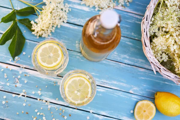 长莓柠檬水与木桌上的糖浆和鲜花瓶的顶视图 — 图库照片