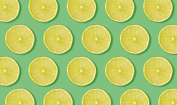Fruit pattern from slices of lime on green background