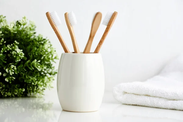 Four bamboo toothbrushes in a mug with a towel — Stock Photo, Image