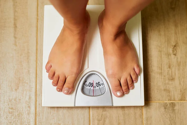 Female bare feet on weight scale in a bathroom — Stock Photo, Image