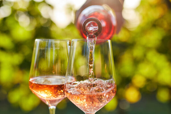 Pouring rose wine into glasses from a bottle