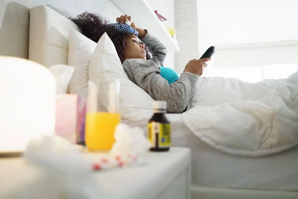 Mulher negra com gripe e frio assistindo TV em casa — Fotografia de Stock