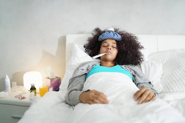 Mujer con fiebre usando termómetro y descansando en la cama — Foto de Stock