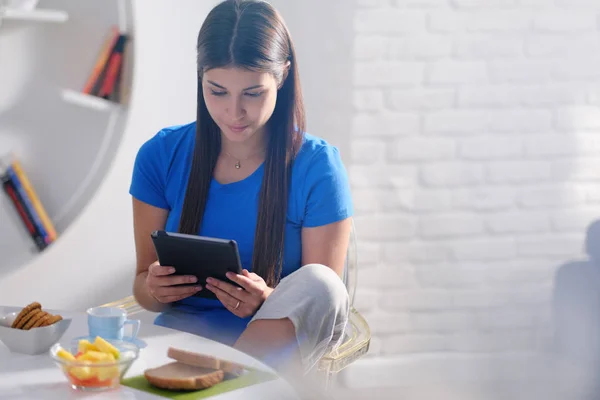 Mujer joven desayunando en casa con la tableta —  Fotos de Stock