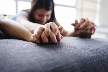 Genç İspanyol çift kanepede, kucaklayan ve ön sevişme sırasında elele yalan. Ön plan eller üzerinde odaklanmak ve uzay kanepede kopyalayın.