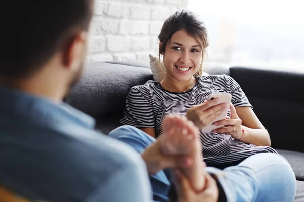 Homme massage copine pieds sur canapé à la maison — Photo