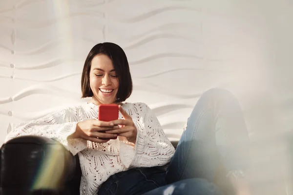 Jong Latino meisje Messaging met mobiele telefoon op de Sofa — Stockfoto