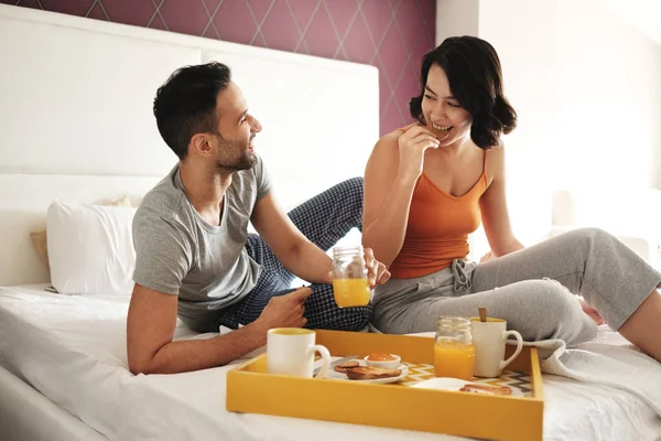 Marido feliz y esposa comiendo desayuno en la cama — Foto de Stock