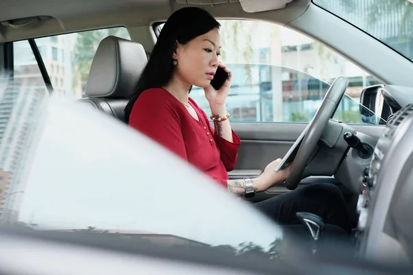 Деловые люди, работающие в автомобиле и разговаривающие по мобильному телефону — стоковое фото