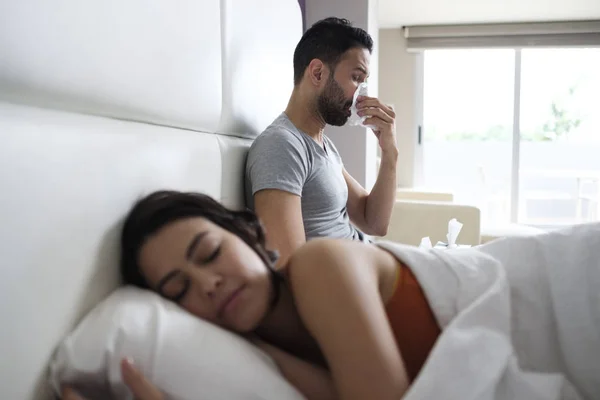 Junger Mann niest nach Erkältung im Bett mit Partner — Stockfoto
