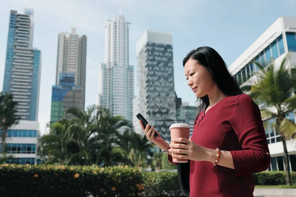 Chinesin mit Telefon geht und trinkt Kaffee — Stockfoto