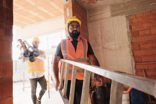 Работники на строительной площадке с использованием инструментов и тяжелого оборудования — стоковое фото
