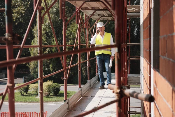 Ingenieur praten op mobiele telefoon In de bouwplaats — Stockfoto