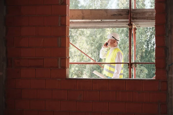 Engenheiro falando no telefone móvel no canteiro de obras — Fotografia de Stock