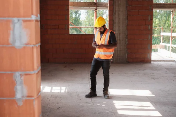 Man aan het werk In de bouwplaats glimlachend en het gebruik van Smartphone — Stockfoto